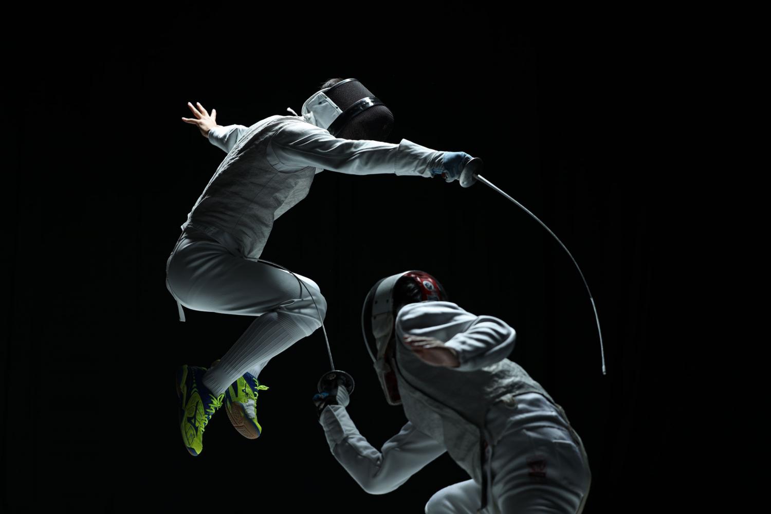 Two competitive fencers mid-combat against a black background, photographed with the Canon RF 70-200mm f2.8L IS USM lens