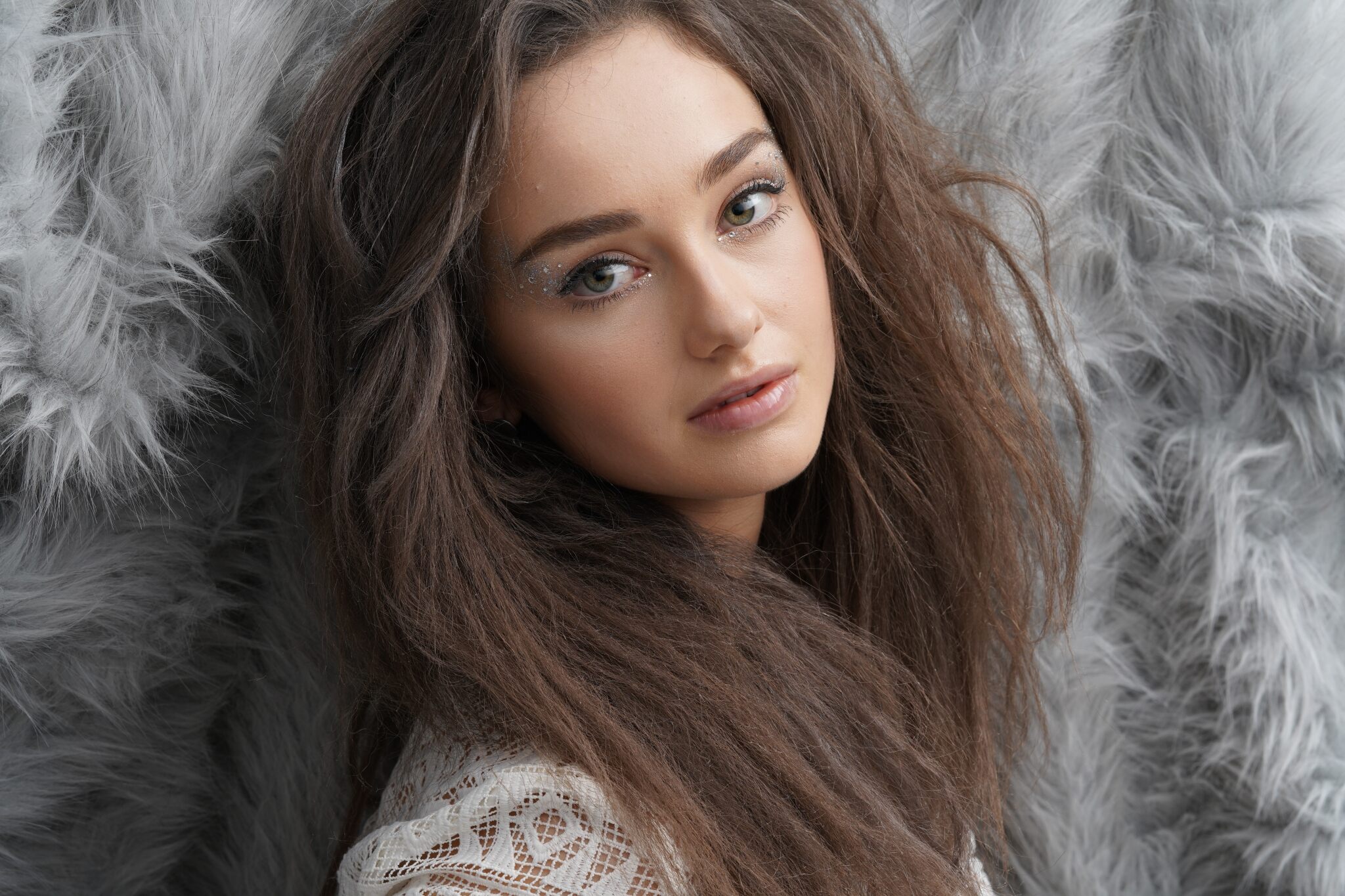 Fashion model with teased brown hair posed against a grey shagpile backdrop, photographed with the Sony a7R Mark IV camera