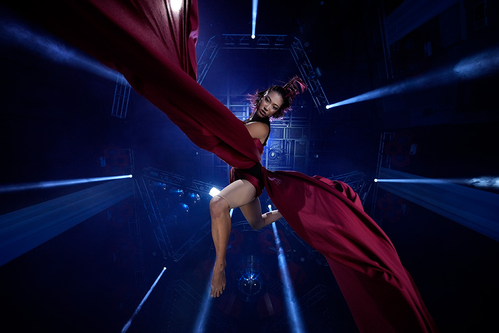 Curtain dancer suspended by billowing maroon silk, shot from below with the Sony a7s III