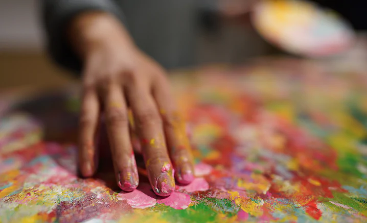 Close-up of artist’s hand fingerpainting in bright colours, photographed with the Sony 24mm 1.4 GM lens