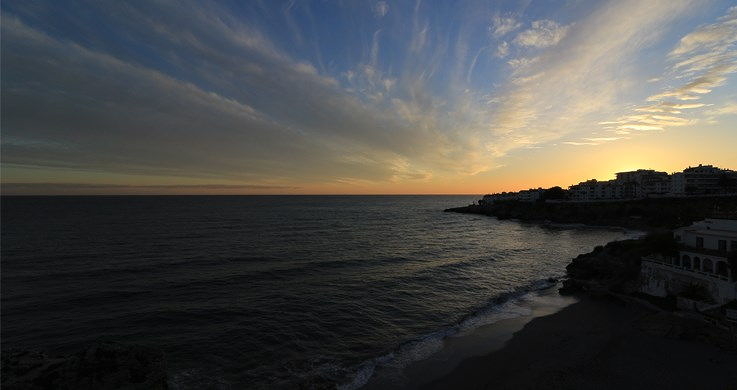 Cloudy sunset over the ocean and a coastal town, photographed with the Canon 10-18mm wide angle lens