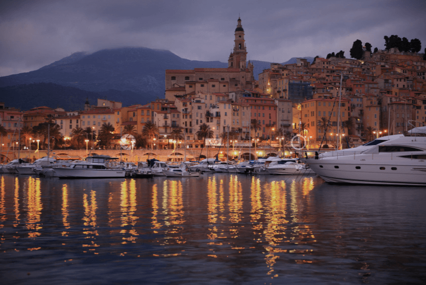 Mediterranean port city at twilight with boats and water in the foreground, shot with the Canon EF 24-70mm f2.8L II USM lens