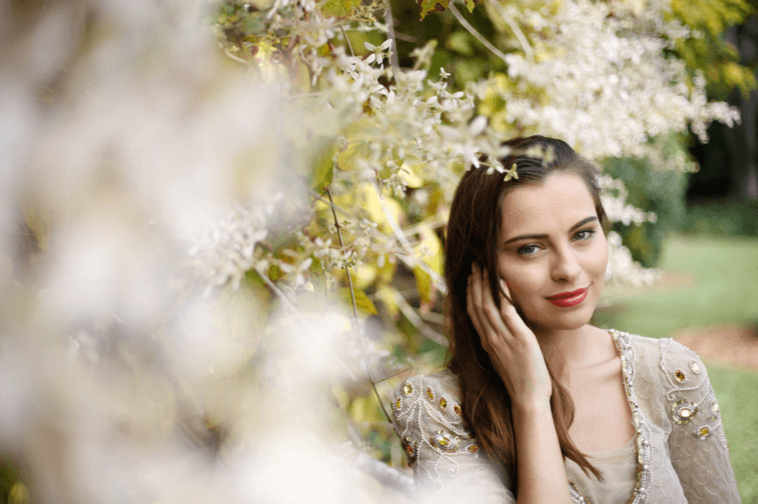 Elegantly dressed young woman with white flowers in the foreground and background, taken with the Canon 50mm 1.8 STM lens