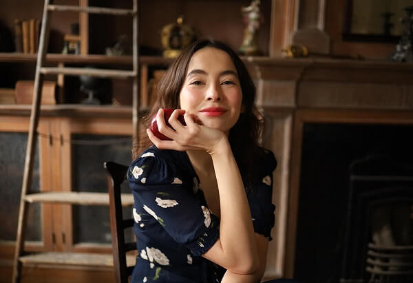 Dark-haired young woman in blue floral dress smiling while holding an apple, photographed with the Canon EOS RP body