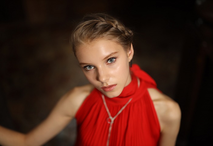 Young woman with braided blonde hair wearing a red halterneck dress, photographed with the Canon RF 50mm f1.2L USM lens