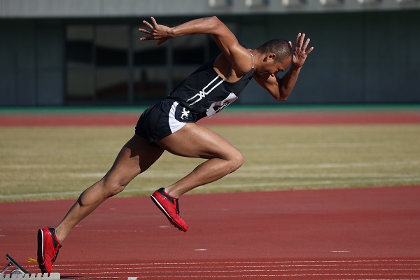 Male track runner launching into a sprint, photographed with the Canon RF 600mm f11 lens