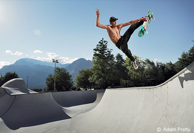 Skateboarder suspended mid-air against a blue sky above a halfpipe, photographed with the Panasonic LUMIX S5 