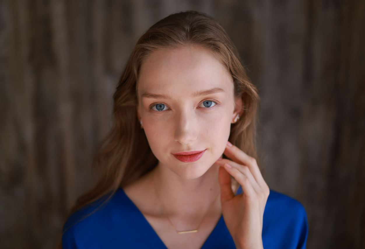 Young woman with blue eyes resting her fingers against her face, photographed with the Canon RF 50mm 1.8 STM Lens