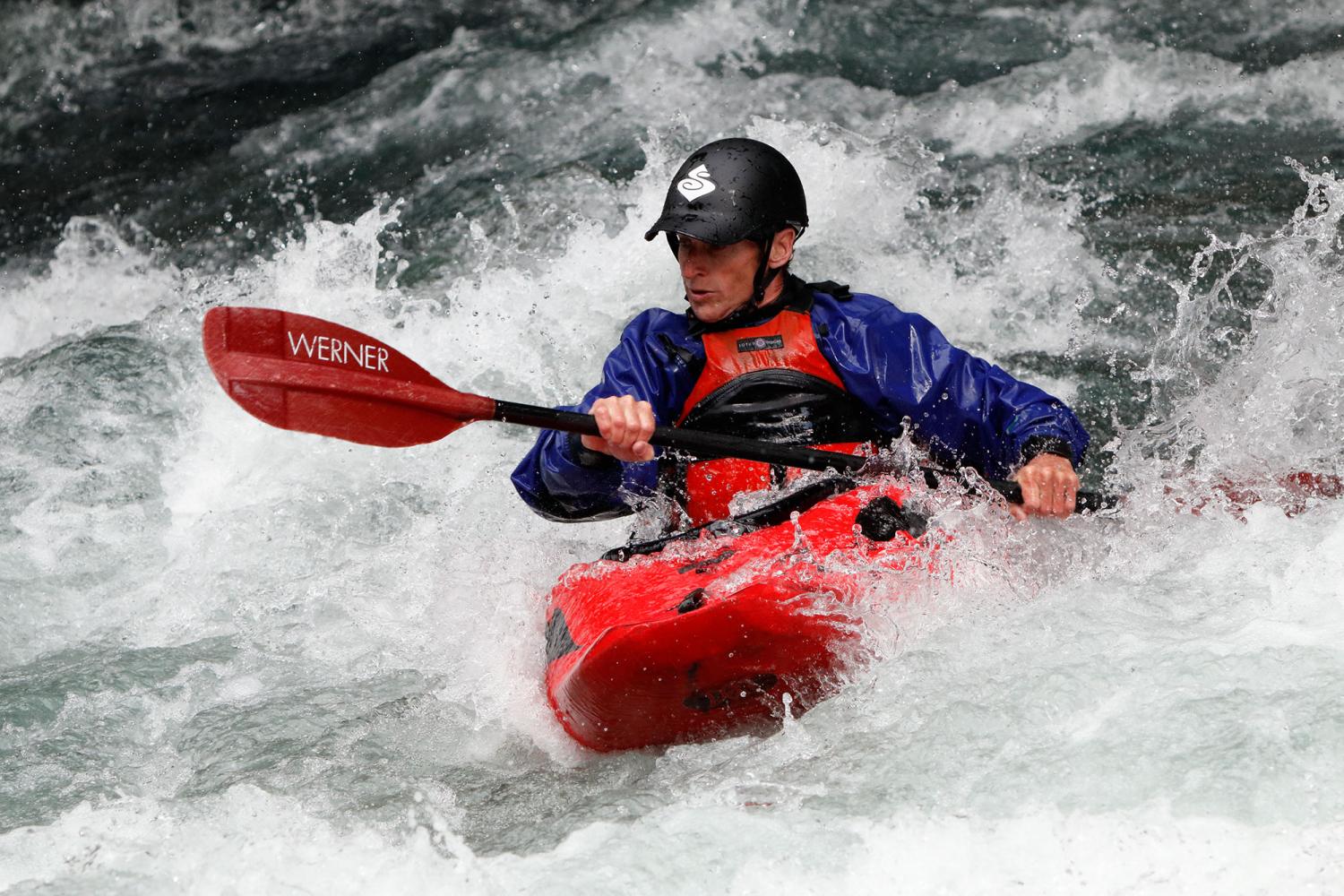 Man in red kayak paddling through white water currents, photographed with the Canon EF 70-300mm f/4-5.6 IS II USM lens