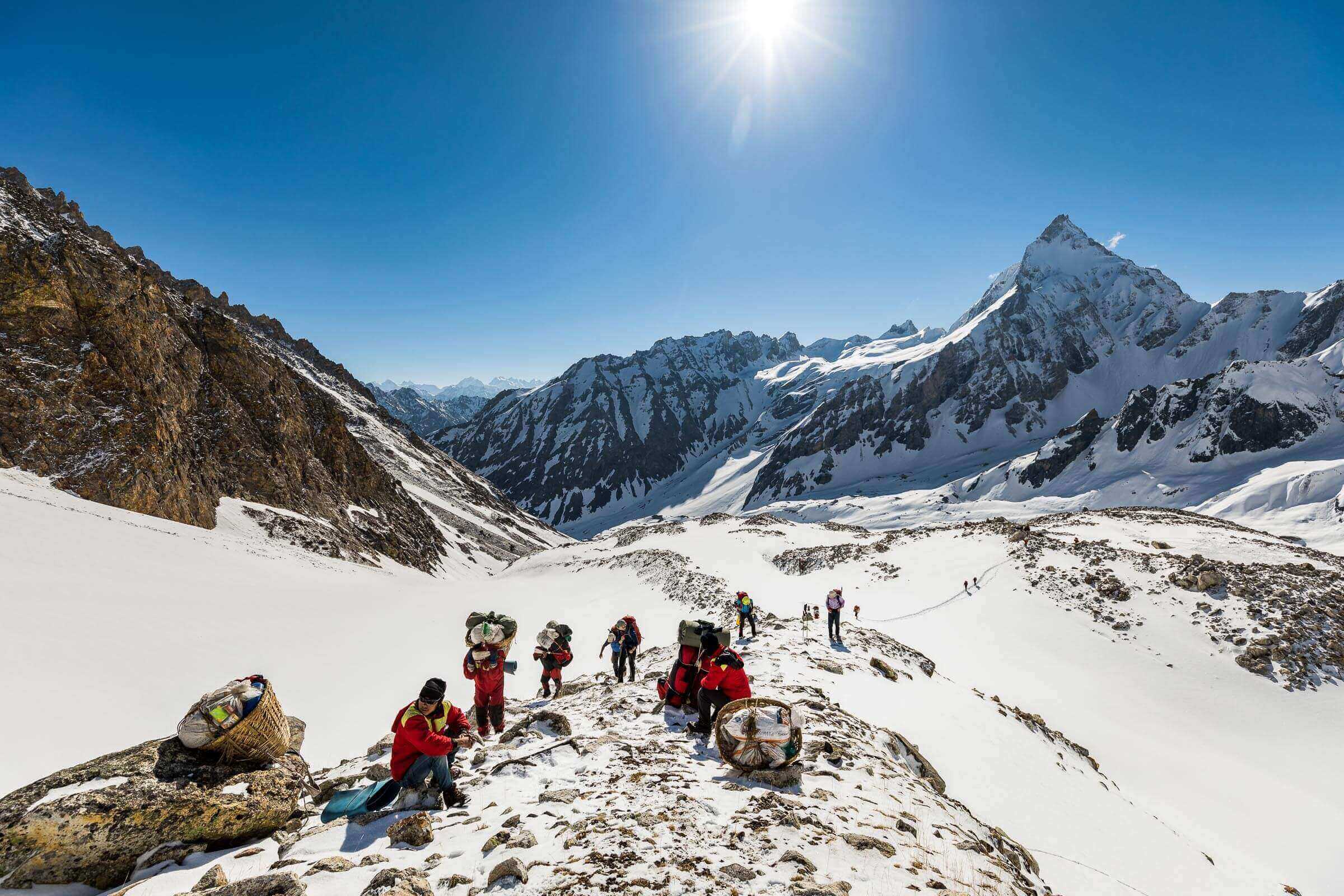 Trekkers and Nepali porters carrying loads up to a high pass in the north-west of Nepal