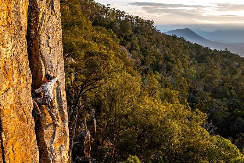 A rock climber, traversing the mountain with a beautiful backdrop, photographed using the Panasonic Lumix S5