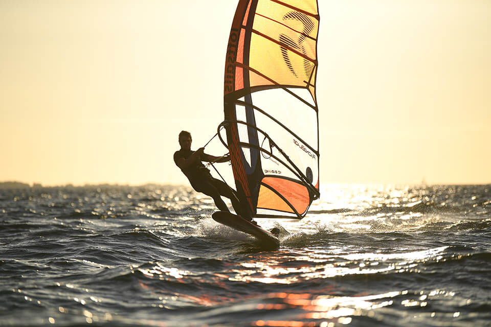 Windsurfer silhouetted against a bright golden sky, photographed with the