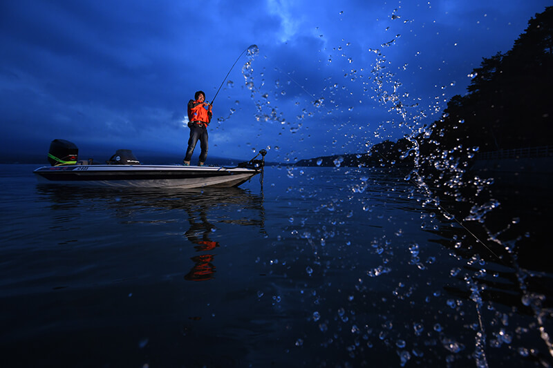 Fisherman standing in a dinghy while holding his fishing rod, with a splash of water in the foreground – photographed using the Nikon SB-5000 flash