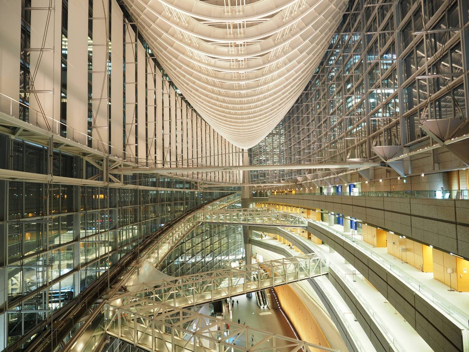 View over large, brightly lit modern atrium with buildings and night sky outside - shot with Olympus 12-45mm f4 PRO Lens