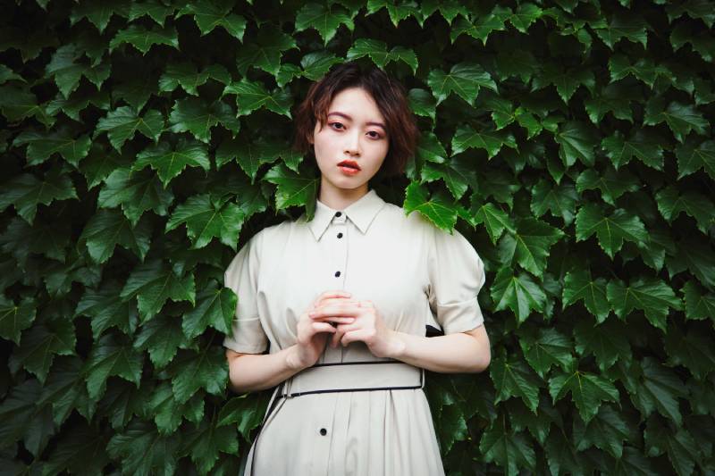 A woman posing in front of a wall with vines, taken using a Panasonic Lumix S 24mm f/1.8 Lens