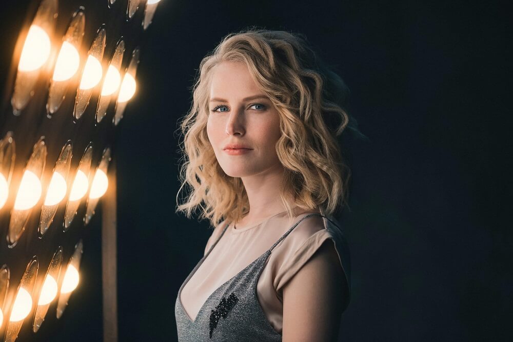 Blonde woman with blue eyes lit by studio lights