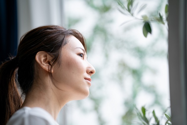 Young Japanese woman looking out a window on an overcast day, photographed with the Sigma 85mm 1.4 Art DG DN Lens for L mount