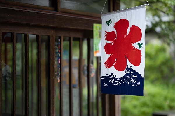 Traditional Japanese fabric banner hanging outside a dark timber shopfront, shot with the Sigma 85mm 1.4 Art DG DN Lens (L mount)