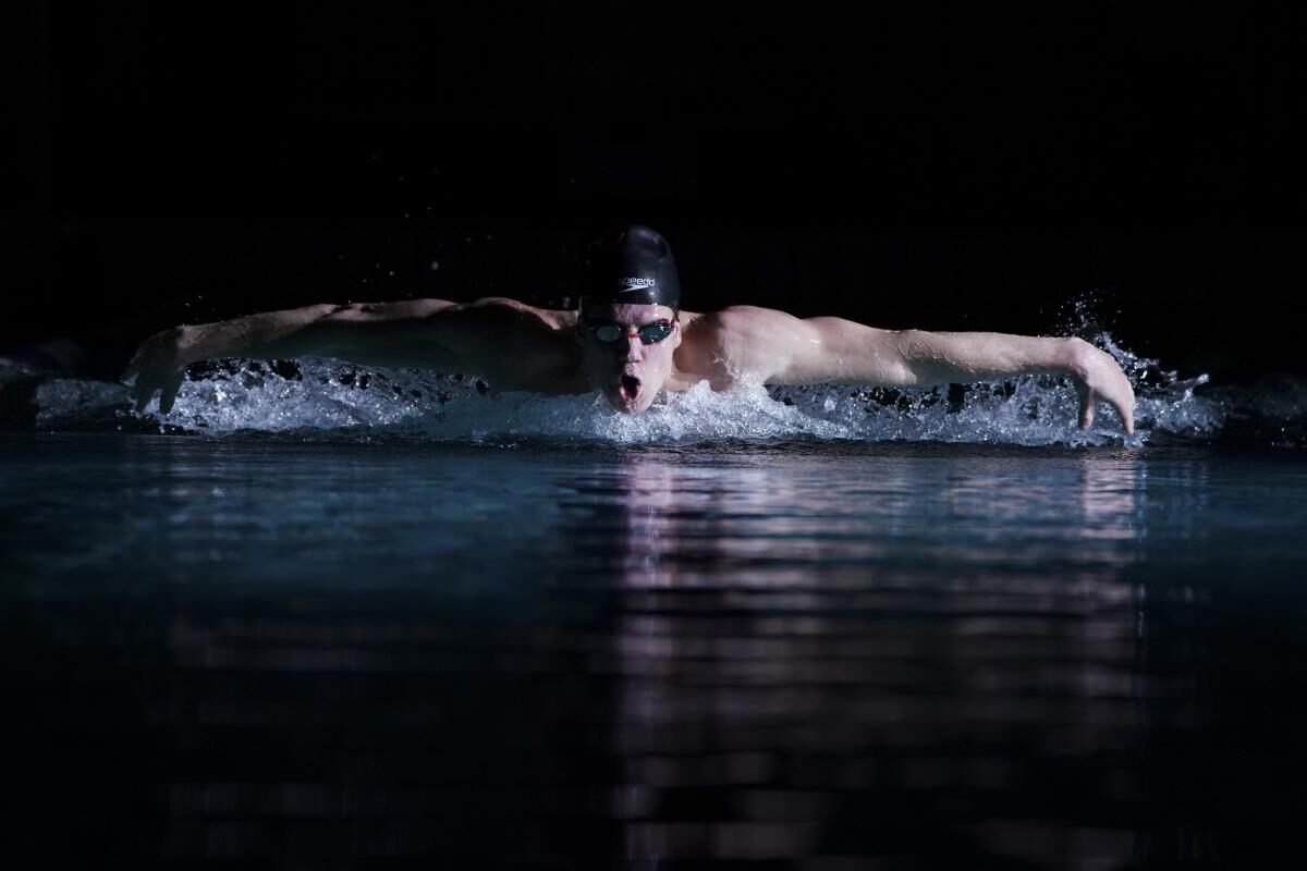 Male swimmer coming up for air midway through butterfly stroke, shot head-on with the Sony FE 100-400mm f/4.5-5.6 GM OSS lens