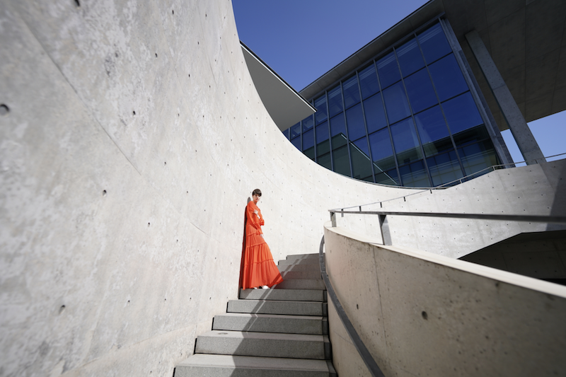 Woman in orange in the middle of a stair, takend with a Sony FE 14mm f/1.8 GM