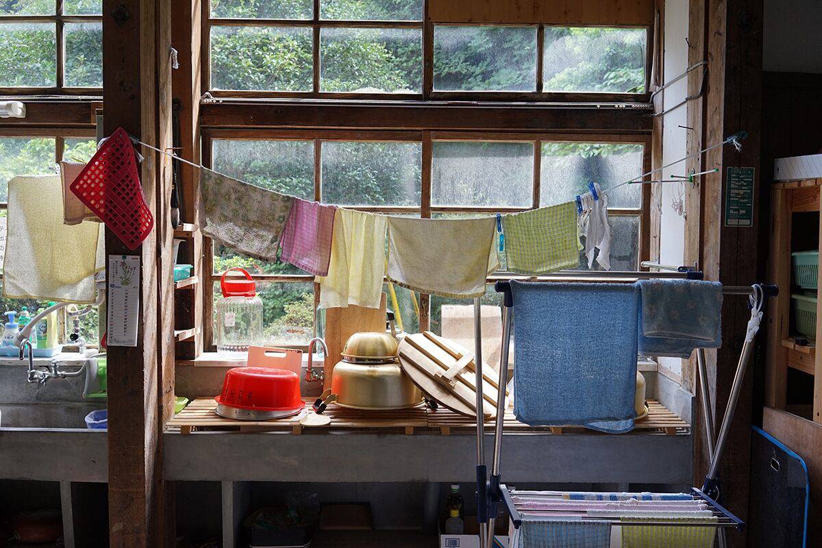 Cloths hung up to dry over a sink stacked with dishes in front of a sash window, shot with the Sony 35mm 2.8 ZEISS lens