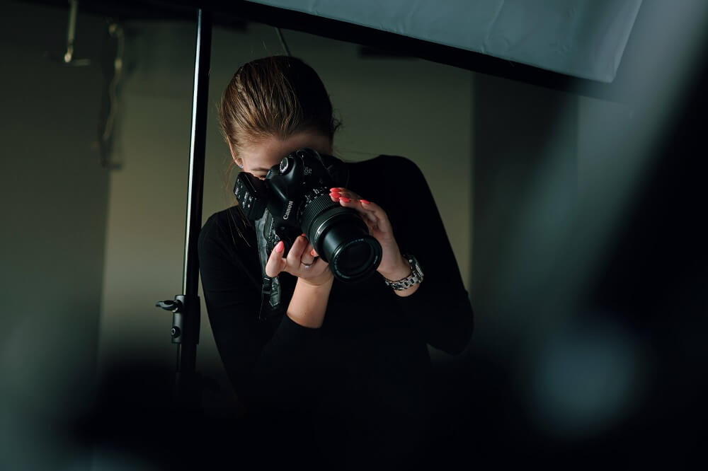 Female photographer using her Canon DSLR inside a photo studio