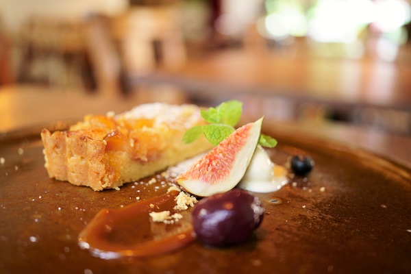 Close-up of frangipane tart slice garnished with fig, caramel and cream, photographed with the Tamron 35mm f2.8 Sony lens