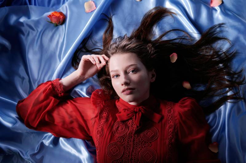 Woman in red lying down a blue satin cloth, taken using a Panasonic Lumix S 35mm f/1.8 Lens