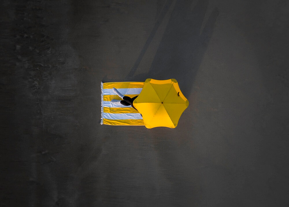 aerial photograph of a person under yellow umbrella