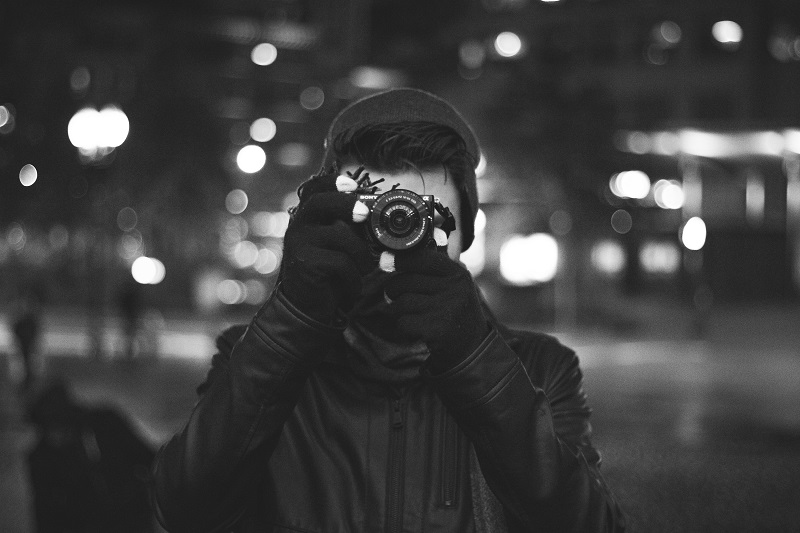 black and white photo of a man taking pictures on the street