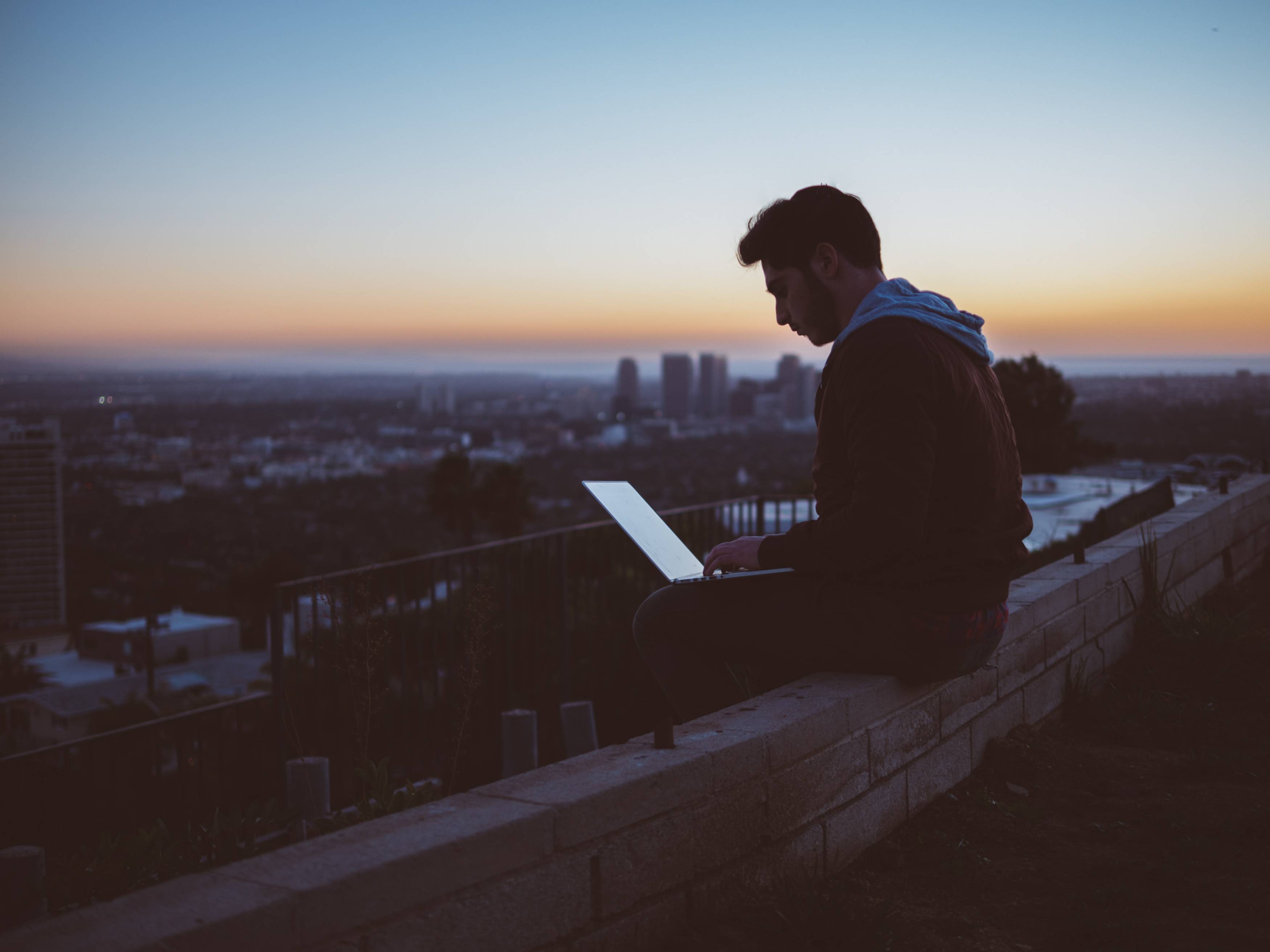 guy using his laptop while on the rooftop of a building