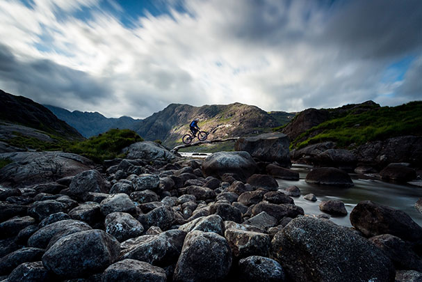 Biker crossing a log, surrounded by rocks, taken using Lee Filters Big Stopper