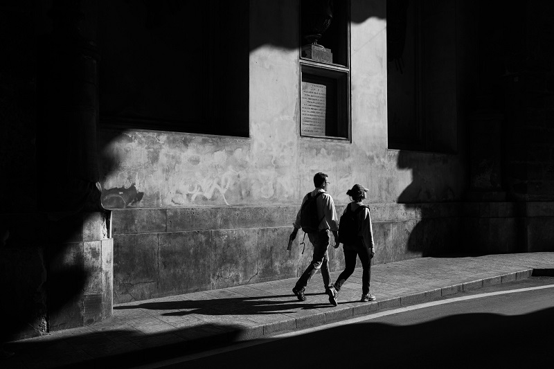 black and white photo of two people walking on the street