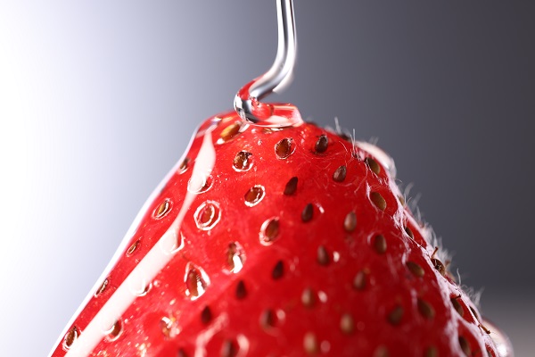 Extreme close-up of strawberry being drizzled with sugar syrup, photographed with the Canon RF 100mm f2.8L Macro IS USM lens