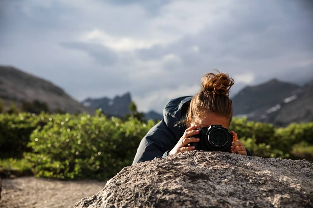 Photographer setting her camera on a rock, preparing to take a picture