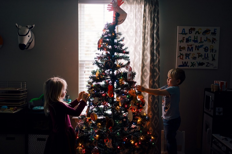 two chidlren hanging ornaments on the christmas tree