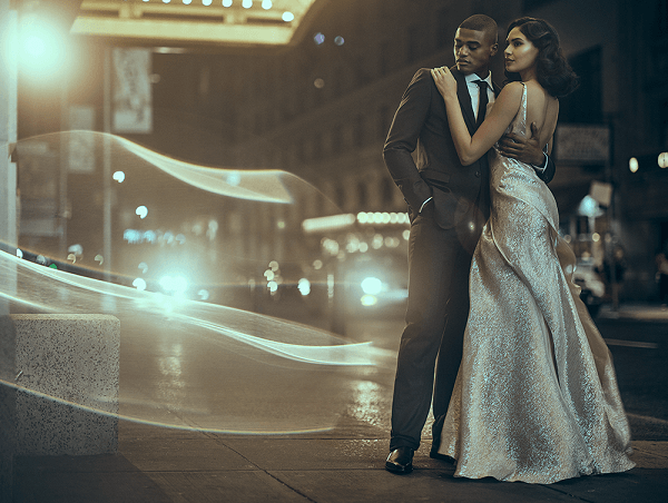 Man in tuxedo clasping a woman in a sparkly gown on New York’s Broadway at night, shot with the Fujifilm GF 80mm f1.7 R WR