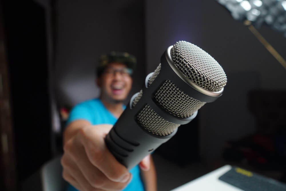 A guy in blue holding a vlogging/podcast microphone