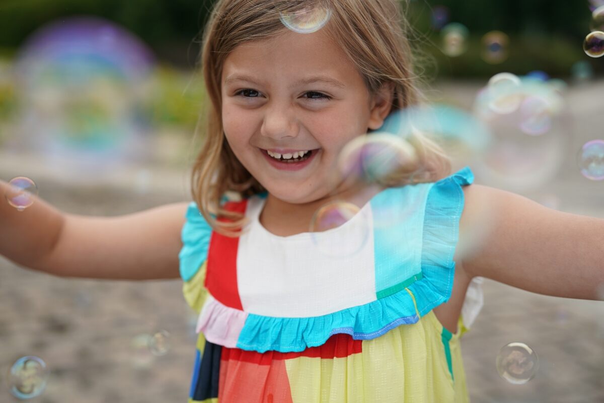 Lifestyle photo of a young smiling girl, surrounded with bubbles