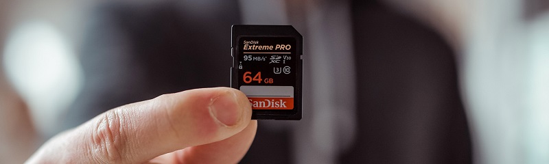 man holding a 64 gb sandisk memory card