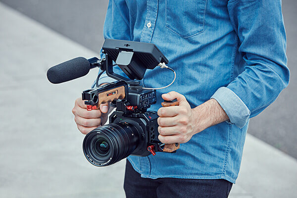 Man in denim shirt holding the Panasonic BGH1 camera by side handles