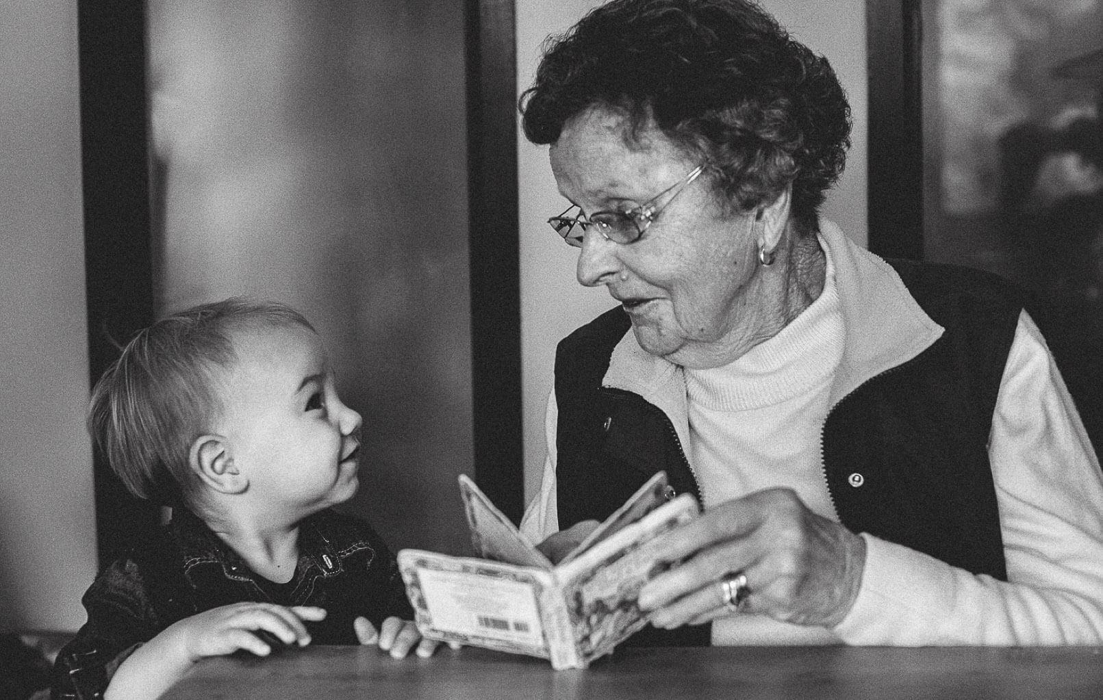 black and white photo of a grandparent reading a book for her grandchild