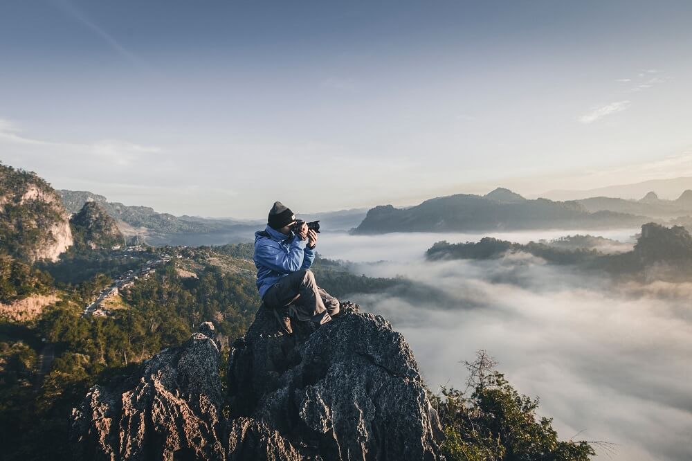 Photographer on a cliff taking a picture of the sea of clouds