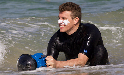 photographer in wetsuit taking photo on the beach