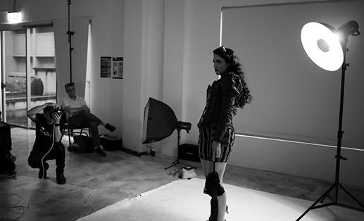 black and white photo of a photographer taking picture of a female model in a studio