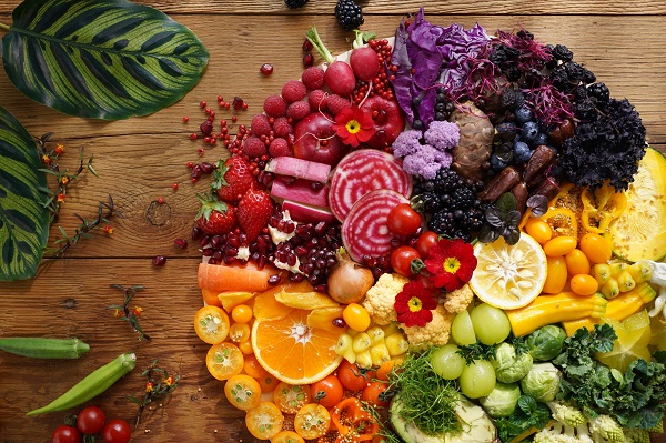 A large round platter of assorted fruit and vegetables grouped by colour, photographed with the Sony 40mm f2.5 G lens