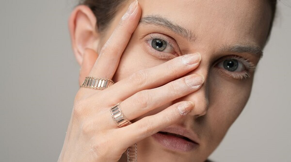 Closeup of a woman finely dusted in white powder who is partly covering her face with one hand, photographed with the Sony a1