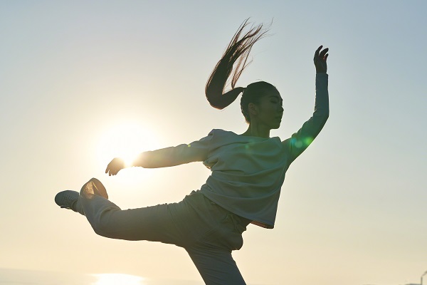 Woman in casual clothing dancing as the sun flares behind her, shot with the Sony FX3 camera