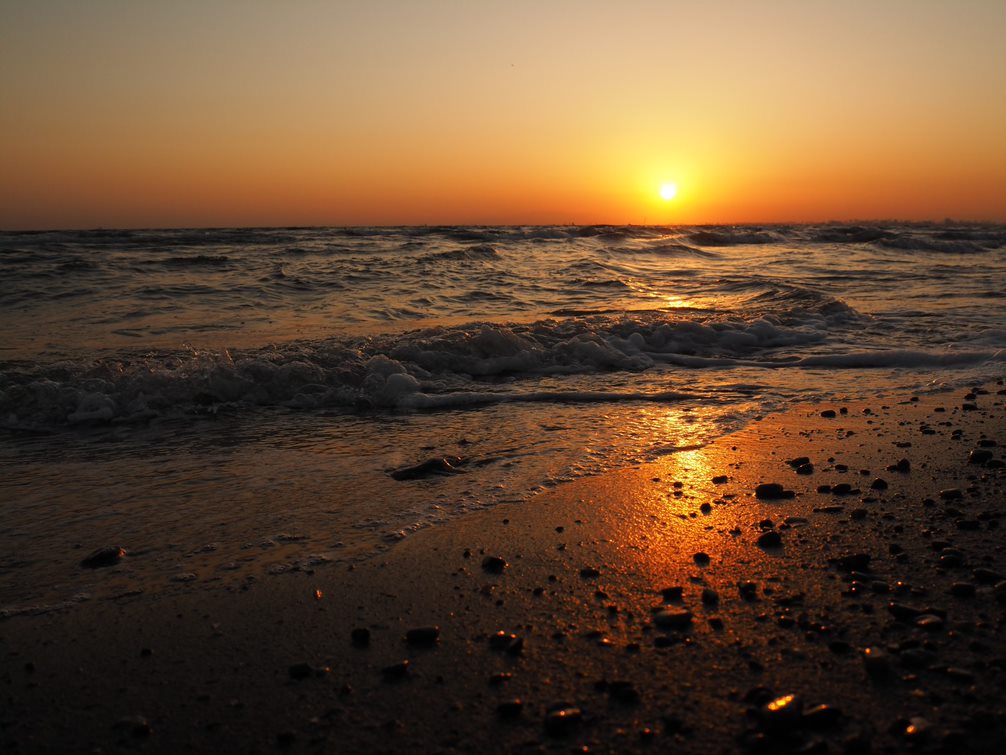 Set over gentle waves and pebble-strewn sand, photographed with the Olympus EM10 Mark IV camera