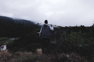 man on the mountain carrying a travel tripod